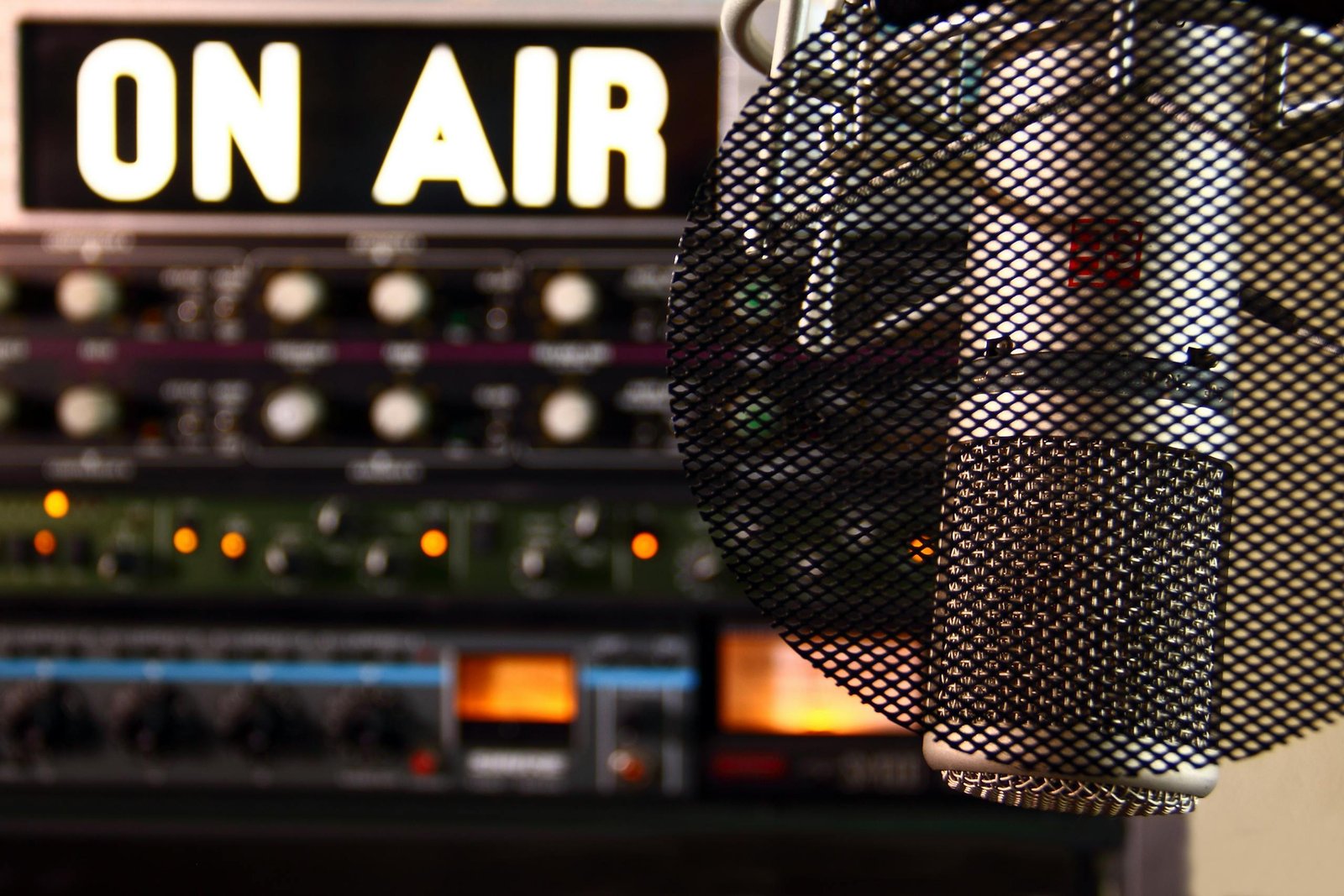Close-up of a radio microphone and control panel in an illuminated studio